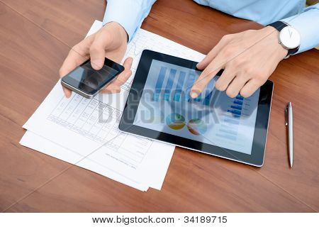 Picture or Photo of Young businessman working with apple ipad and iphone in the office.