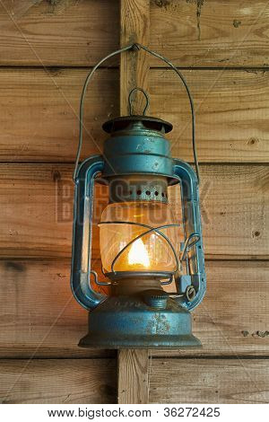Picture or Photo of Rusty lit blue lantern hanging in an old shed