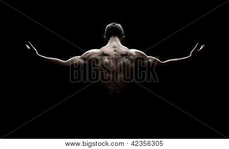Picture or Photo of Rear view of healthy young man with his arms stretched out isolated on black background
