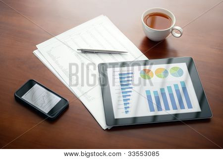 Picture or Photo of Modern workplace with apple ipad and iphone, pen and papers with numbers.