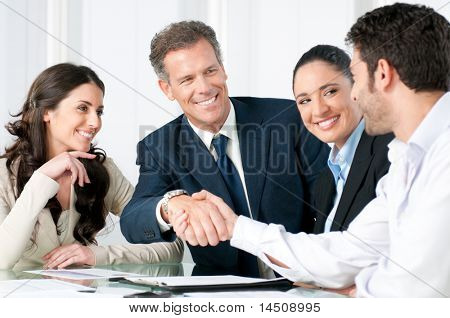 Picture or Photo of Mature businessman shaking hands to seal a deal with his partner and colleagues in a modern office