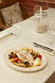 Sea bass fillet baked with vegetables, Italian dish, on restaurant table