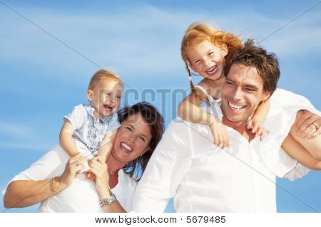 Picture or Photo of Young happy family having fun outdoors dressed in white and with blue sky in background