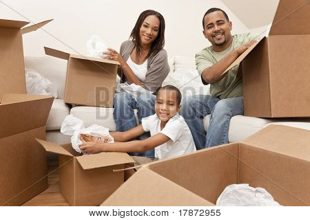 Picture or Photo of African American family, parents and son, unpacking boxes and moving into a new home, The adults are unpacking crockery, the child is unpacking a toy airplane.
