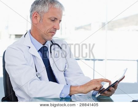 Picture or Photo of Serious doctor working with a tablet computer in his office