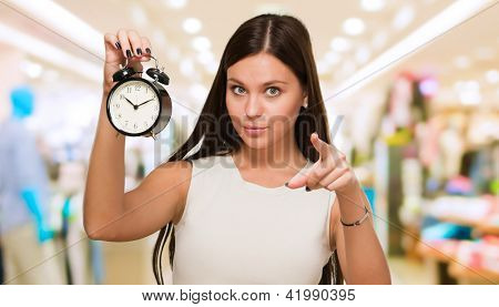 Picture or Photo of Young Woman Holding Clock And Pointing at a mall